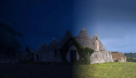 Stone ruins of a small church or chapel with peaked roof silhouetted against twilight sky.