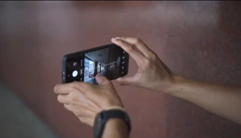 Hands holding a smartphone in landscape orientation while photographing an illuminated interior space.