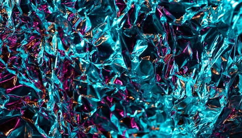 Abstract macro photograph of shattered glass or ice crystals with cyan, magenta, and dark tones.