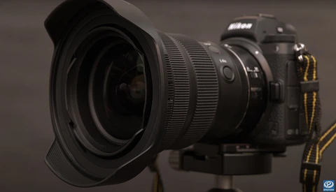 Nikon DSLR camera with wide-angle lens mounted on tripod against neutral background.