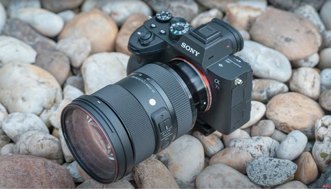 Sony mirrorless camera with sigma lens on rocky ground.