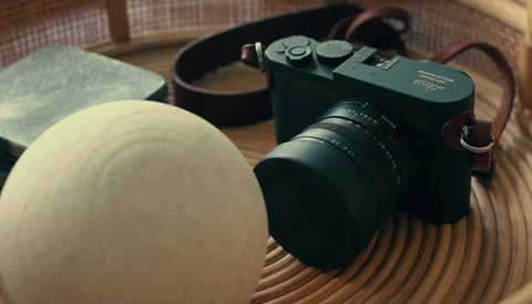 Rangefinder camera with lens and accessories arranged on a wooden surface.
