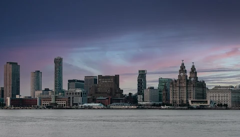 Waterfront cityscape at twilight with modern and historic towers reflected in calm water.