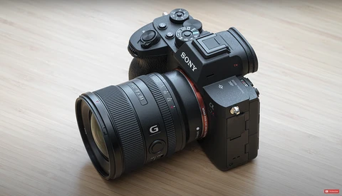 Sony mirrorless camera with Sony G-series lens mounted, displayed on light wood surface.