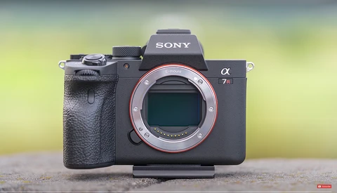 Sony α7 III mirrorless camera body with open mirror box, displayed against a blurred yellow-green background.