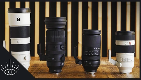 Four telephoto lenses arranged on a wooden surface against a striped gold and cream backdrop.
