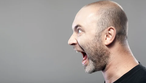 Man in profile with open mouth expressing surprise or excitement against neutral gray background.