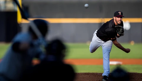 Pitcher mid-delivery throwing a baseball from the mound, captured with selective focus on the athlete.