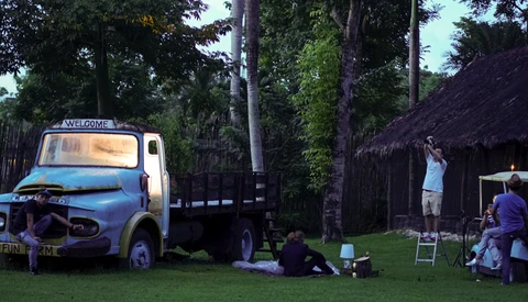 Vintage truck converted into a mobile bar or café setup at an outdoor event surrounded by tall palms and thatched structures.
