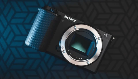 Sony mirrorless camera body with lens mount exposed, positioned on blue and black geometric patterned surface.