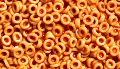 Overhead view of golden breakfast cereal rings with holes, densely packed and filling the entire frame.