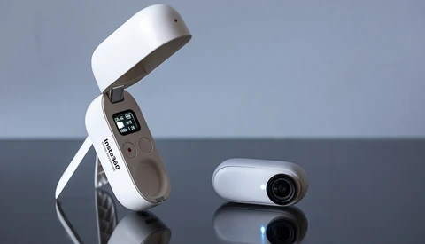 Two compact white and gray devices displayed on a reflective surface against a blue-gray background.