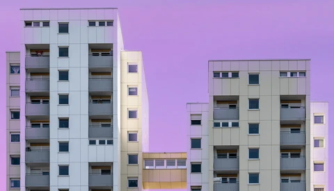 Modern apartment buildings photographed against a vibrant purple twilight sky.