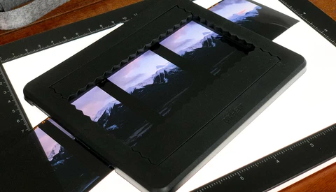 Film strip contact sheet displayed on a black light table alongside rulers and photographic prints.