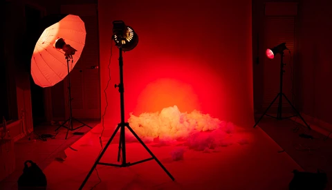 Professional studio setup with red-gelled lighting rigs creating atmospheric smoke effect.