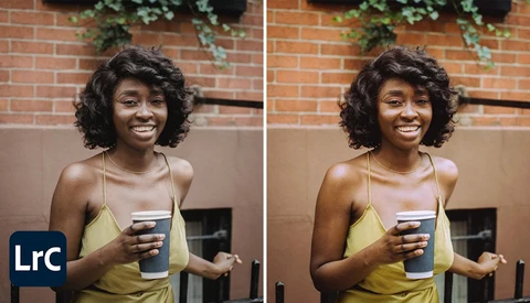 Woman in yellow halter top holding coffee cup, smiling at camera against brick wall backdrop.