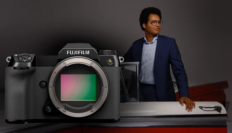 Fujifilm mirrorless camera with colorful sensor display next to standing professional.
