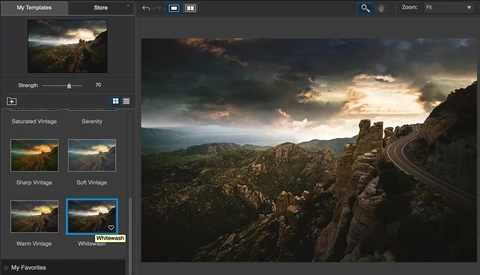 Mountain landscape with winding road at sunset, stormy sky with golden light breaking through clouds.
