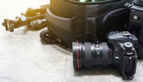 Professional DSLR camera with wide-angle lens on marble surface next to camera bag.