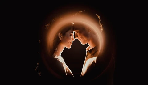Profile silhouette of a person backlit by warm, glowing concentric circles against a dark background.