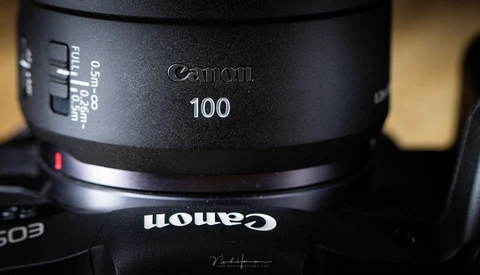 Canon 100mm telephoto lens barrel with focus ring and distance markings visible.
