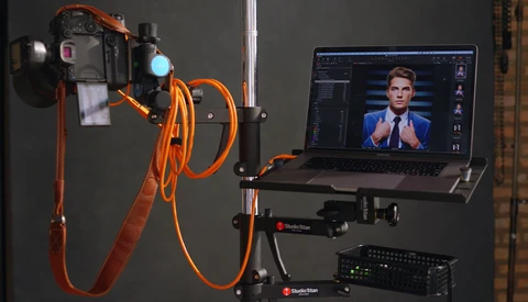 Professional lighting setup with LED panel, orange cables, and laptop displaying portrait editing software.