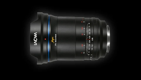 LAOWA wide-angle lens with blue ring and focus ring against dark background.