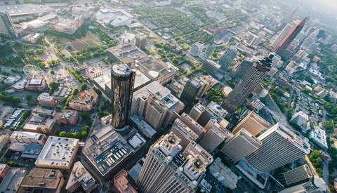 Aerial view of downtown urban skyline with tall buildings and green spaces between structures.