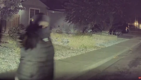 Blurred figure in motion on a nighttime residential street with thermal or infrared color grading.