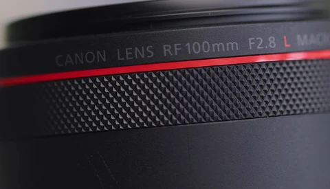 Canon RF 100mm F2.8 L macro lens barrel with red accent stripe and textured grip surface.