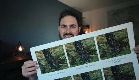 Photographer holding a contact sheet displaying multiple frames of a moss-covered tree in forest setting.