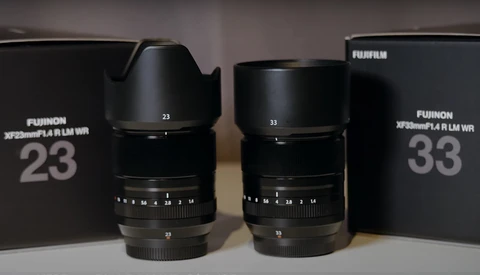 Two Fujifilm XF prime lenses with hoods displayed alongside their original boxes.