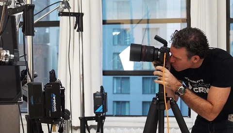 Cameraman operating a professional video camera on a tripod in a high-rise interior.