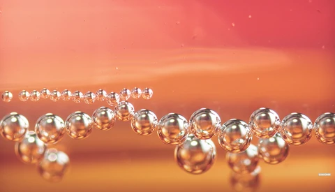 Water droplets arranged in curved lines against a warm orange and red gradient background.