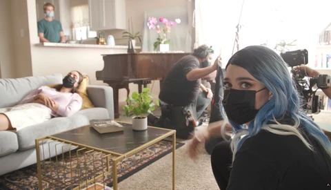 Behind-the-scenes photo of a residential interior shoot with camera operator and lighting crew.