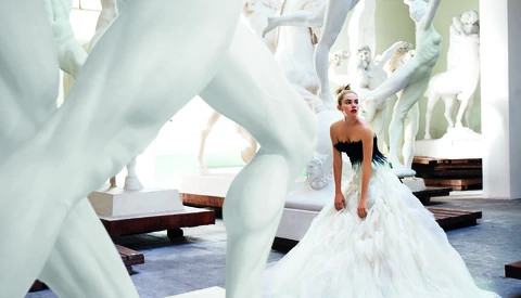 Bride in white gown posed among large white sculptural forms in modern gallery setting.
