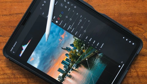 iPad displaying a landscape photo with editing interface and Apple Pencil resting on screen.