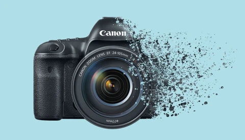 Canon EOS R5 mirrorless camera with 24-105mm lens against light blue background, right side fragmenting into particle effects.