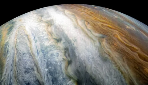 Close-up of Jupiter's cloud bands showing swirling atmospheric patterns in white, tan, and gray tones.