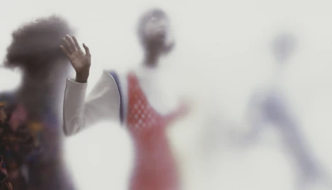 Silhouetted figures with raised hands in soft focus against a bright, hazy background.