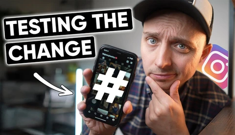 Person holding a smartphone with a hashtag symbol displayed on screen, with text overlay reading 'TESTING THE CHANGE'.