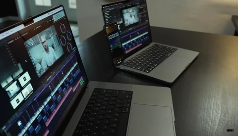 Video editing workstation with multiple monitors displaying timeline and color correction software.