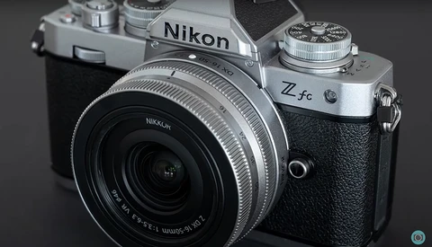Nikon Z fc mirrorless camera with attached lens, shown against a neutral gray background.