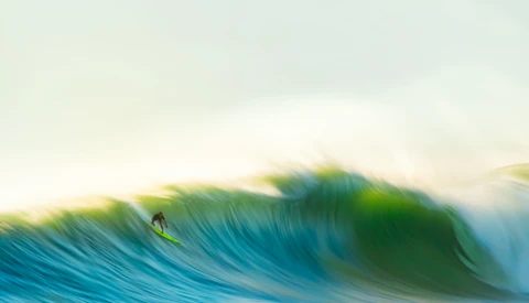 A surfer riding inside a barrel on a large ocean wave with dynamic motion blur effect.