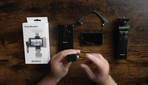 Sony vlogging equipment laid out on wood surface: camera, monitor, microphone, and packaging.