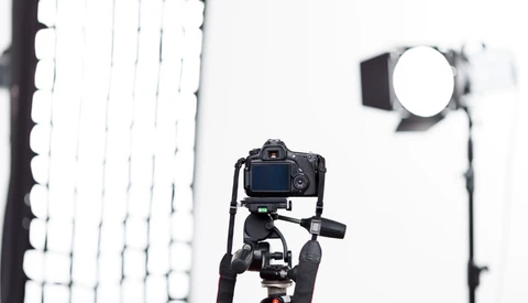 DSLR camera mounted on tripod with studio lighting setup in background.