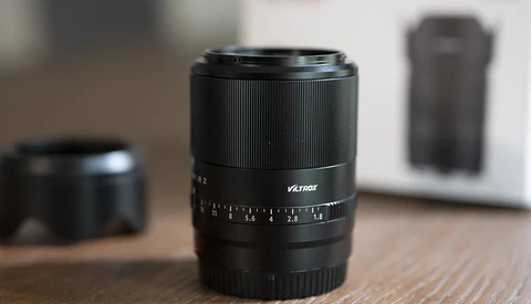 Viltrox prime lens with focus ring and aperture scale on wooden surface.
