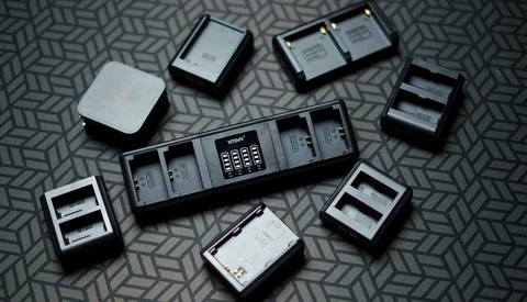 Collection of camera battery chargers and batteries arranged on a patterned surface.