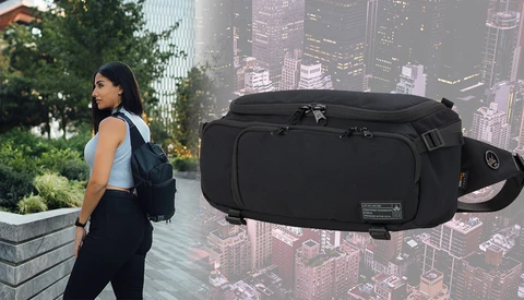 Woman wearing black travel backpack and waist bag against urban cityscape backdrop.