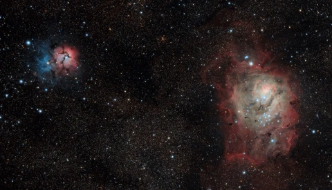 Deep space photograph showing two nebulae with blue and red emission clouds surrounded by stars.